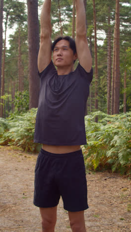 Vertical-Video-Of-Man-Warming-Up-And-Stretching-Before-Work-Out-Exercising-Running-Through-Forest-Shot-In-Real-Time